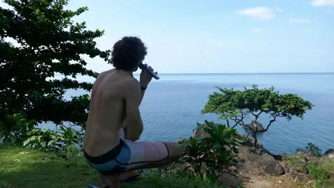 A man cuts his beard in nature at a campsite with a view of the sea Stock Footage 293273360