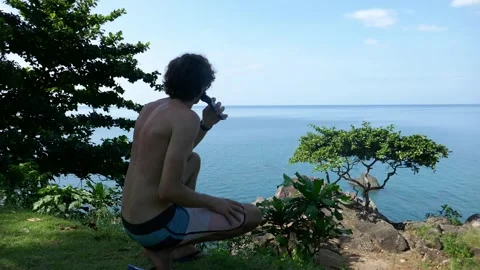 A man cuts his beard in nature at a campsite with a view of the sea Stock Footage 293273403