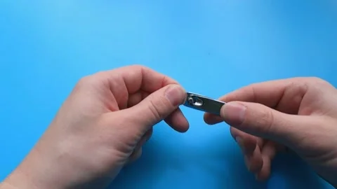 The man cuts his nails with scissors on a blue background Vídeo Stock 150782296