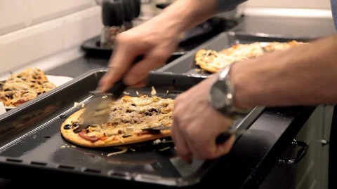 A man cuts up a hot pizza on the kitchen table Stock Footage 72313370