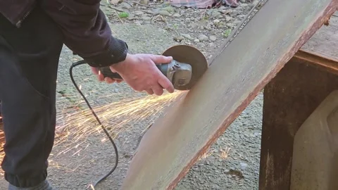 A man cuts an iron sheet with a grinder, sparks fly. Hand work. Stock Footage 296829509