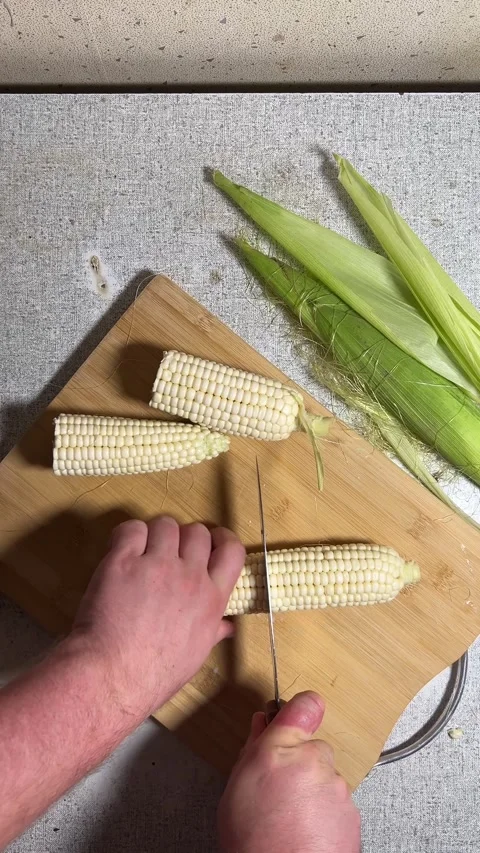 Man cuts with knife and breaks fresh raw cob of white corn in half Stock Footage 280854074