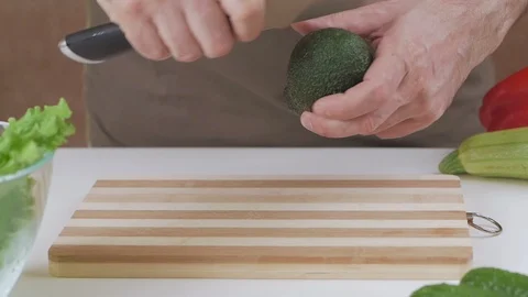 A man cuts with a knife an avocado into two halves Stock Footage 101807749