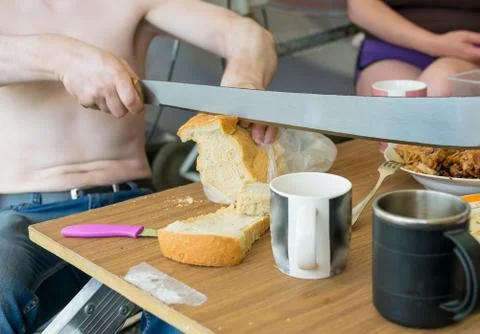 Man cuts a loaf of bread with a machete Stock Photos