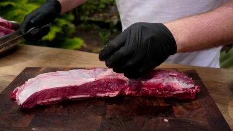 A man cuts meat with a knife and separates fat. 4K shooting Stock Footage 131873553