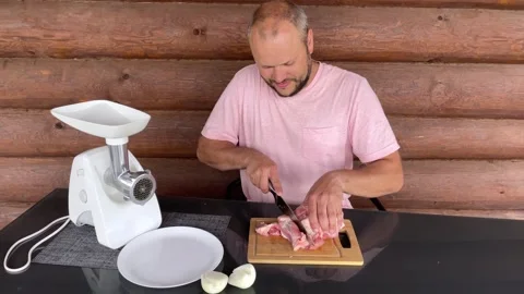 A man cuts meat into pieces to send it to a meat grinder Stock Footage 246331153
