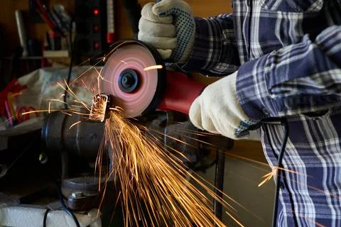 A man cuts metal with an angle grinder 스톡 사진