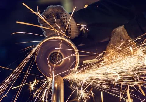 A man cuts metal using an angle grinder close-up. Many sparks Stock Photos