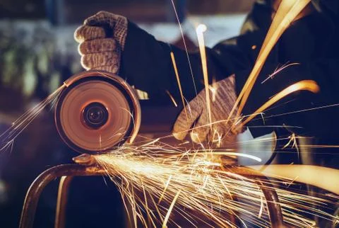 A man cuts metal using an angle grinder close-up. Many sparks Stock Photos