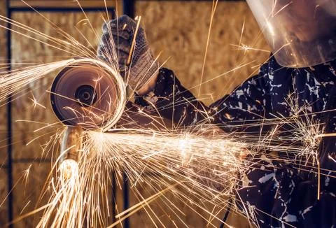 A man cuts metal using an angle grinder close-up. Many sparks Stock Photos