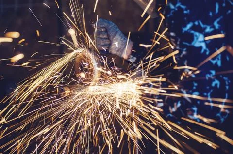 A man cuts metal using an angle grinder close-up. Many sparks Stock Photos