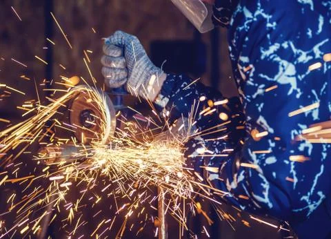 A man cuts metal using an angle grinder close-up. Many sparks Stock Photos
