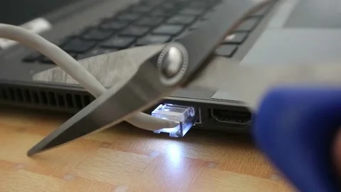 Man cuts the Network Cable into a laptop with scissors. Cut the internet Stock Footage 196803371