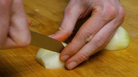 The man cuts the onion and chops the onion. Close shot of a onion. 4K Stock Footage 128589218