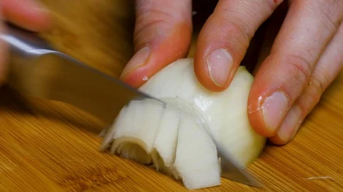 The man cuts the onion and chops the onion. Close shot of a onion. 4K Stock Footage 128590446