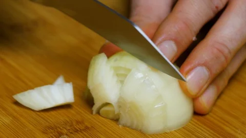 The man cuts the onion and chops the onion. Close shot of a onion. 4K Stock Footage 128591098