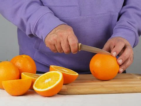 A man cuts oranges Stock Photos