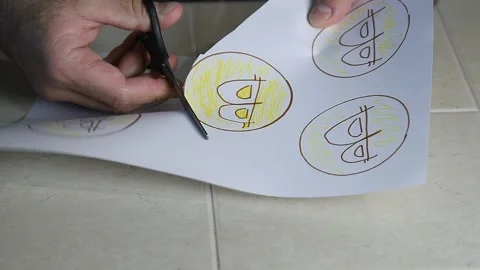 A man cuts out a bitcoin drawn on paper with scissors. Stock Footage 145094240