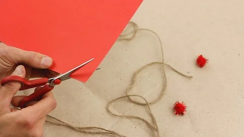 Man cuts out small red paper heart, craft gift for valentine day, top view Video stock 122419643