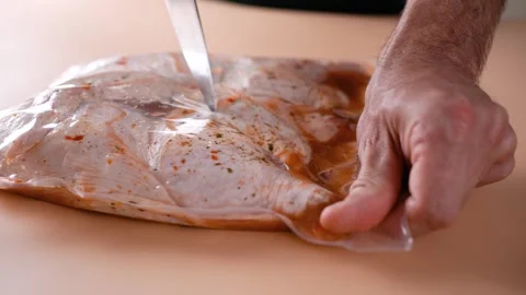 A man cuts a package for baking with chicken before cooking. Stock Footage 250324665
