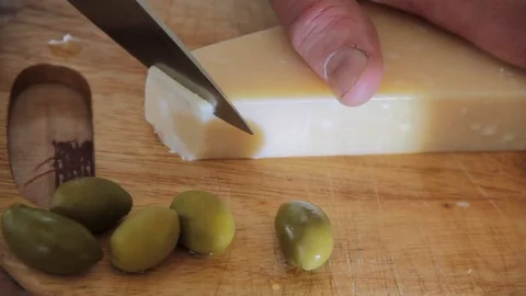 Man cuts parmesan cheese olives, wooden board Stock Footage 80349739