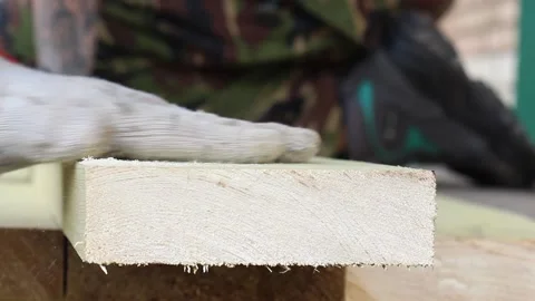 A man cuts off part of the board with a rusty hacksaw and removes the sawdust Stock Footage 132194876