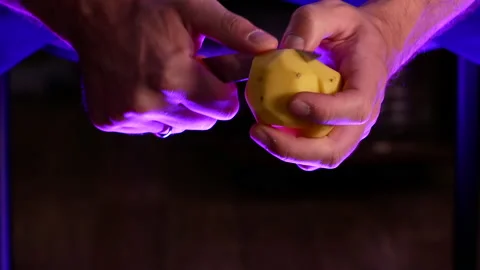 A man cuts a peeled potato in two Stock Footage 165569606