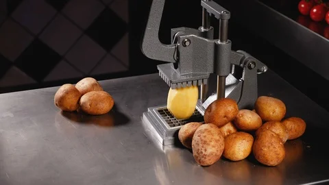 A man cuts peeled potatoes with a big french fries cutter. Close up Stock Footage 128294571