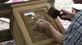 Man cuts a picture with elephants out of wood at a teak factory in Thailand HD Footage