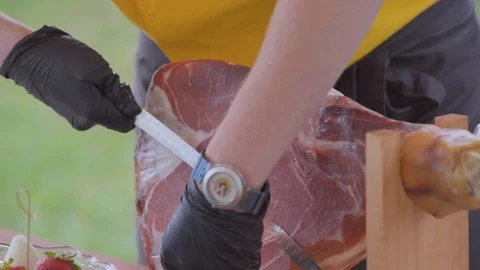 A man cuts off a piece of ham Stock Footage 103395482