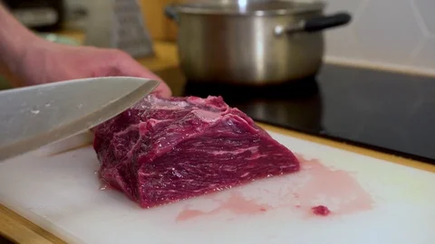A man cuts a piece of meat, beef on a cutting Board in the kitchen Stock Footage 129100923