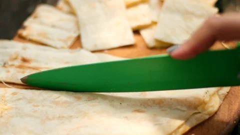 Man cuts pita bread into small pieces with a green knife at a picnic in nature Stock-Footage 115471694