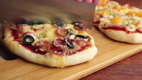 Man cuts pizza with cleaver on cutting board close up Stock Footage 147192890