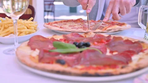 A man cuts pizza at a table in an Italian restaurant. Vidéo 131697611