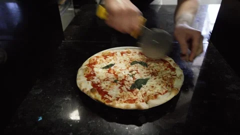A man cuts a pizza into triangular pieces Stock Footage 261018391