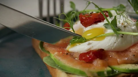 A man cuts a poached egg into salmon sandwiches Stock Footage 204028846
