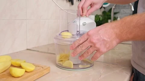 A man cuts potatoes into thin slices in food processor. Preparation of potatoes Stock Footage 224515564