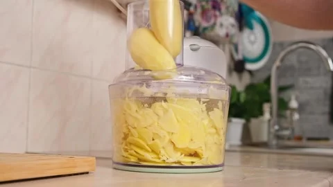 A man cuts potatoes into thin slices in food processor. Preparation of potatoes Stock Footage 229928147