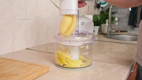 A man cuts potatoes into thin slices in food processor. Preparation of potatoes Stock Footage 231517862