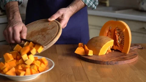 Man cuts pumpkin in the kitchen at home preparing for Thanksgiving dinner Stock Footage 119934315