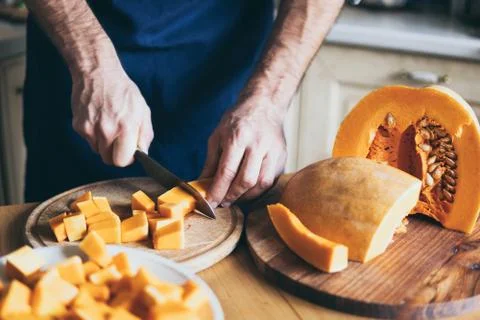 Man cuts pumpkin in the kitchen Stock Photos