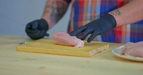 Man cuts raw chicken meat on a wooden board. Close-up, chicken meat fillet cut Stock Footage 131137904