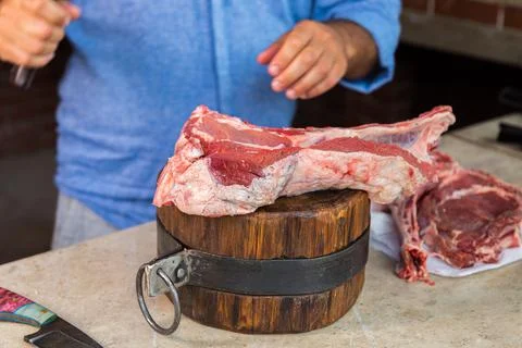 A man cuts raw meat on a deck. Fresh meat on a cutting board. Stock Photos