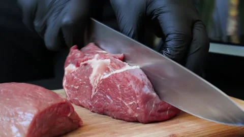 Man cuts raw meat with a knife Видео 200204138