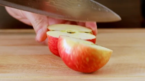 Man cuts red apple with kitchen knife on wooden board Stock Footage 128333539
