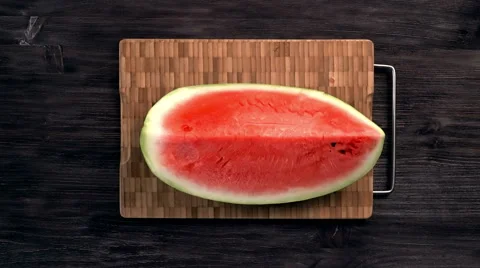Man cuts red juicy ripe watermelon in slices with knife on dark background Stock Footage 65515341