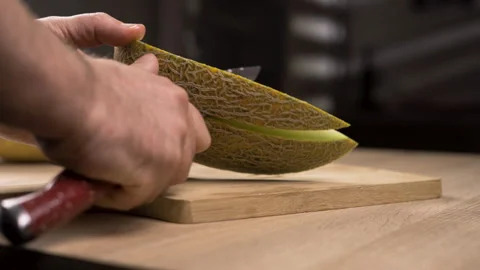 Man cuts ripe melon into slices using knife. Juicy fruit preparation. vegetarian Stock Footage 319022654