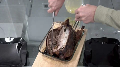A man cuts up a roast duck with a fork and a large knife on a glass platter 스톡 동영상 143141218