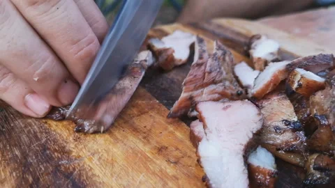 A man cuts Roast pork into large pieces on a wooden board. Stock-Footage 140487743