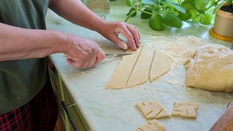 A man cuts rolled dough on a kitchen table. Stock Footage 307008662